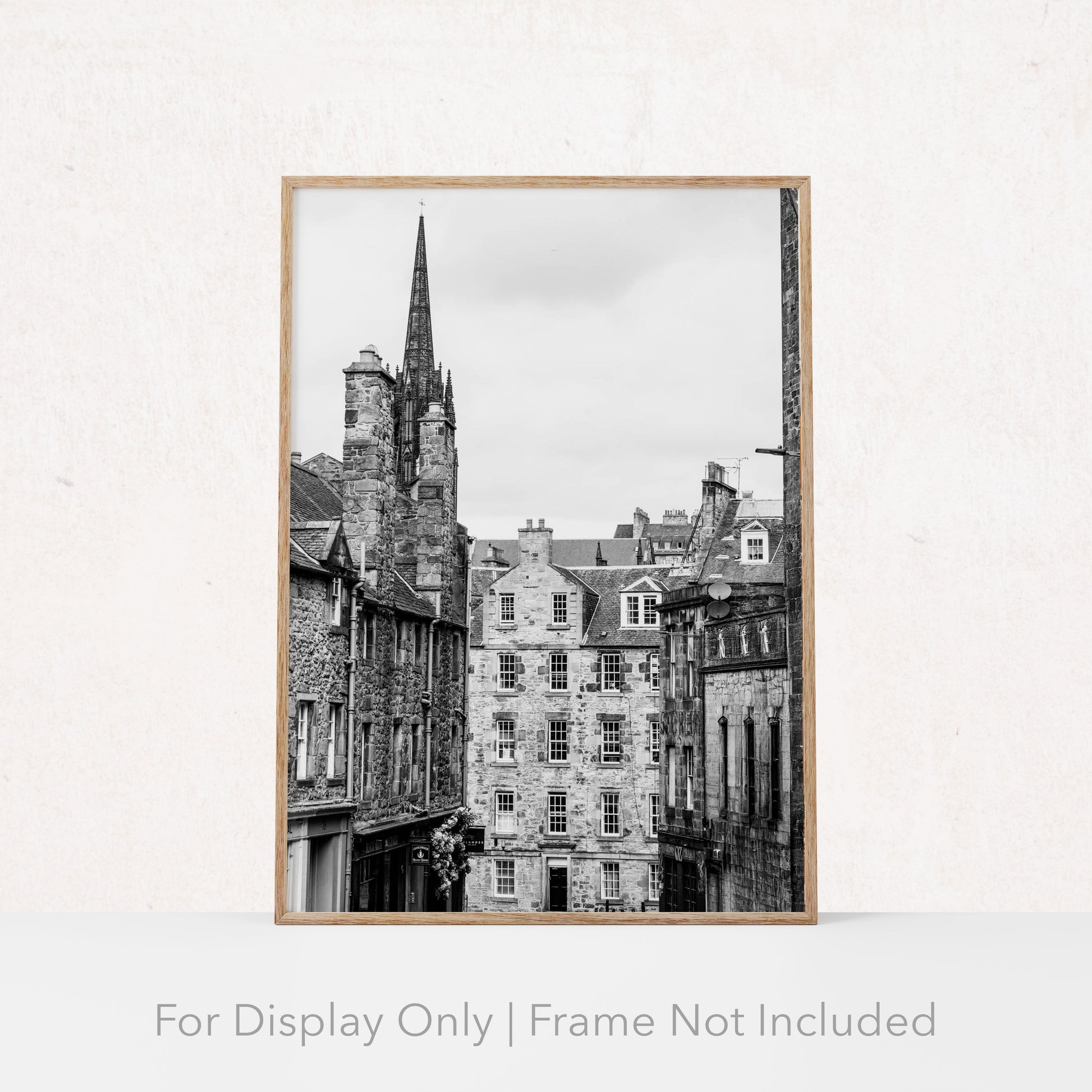Black and white photograph of an Edinburgh street with historic stone architecture and a church spire.