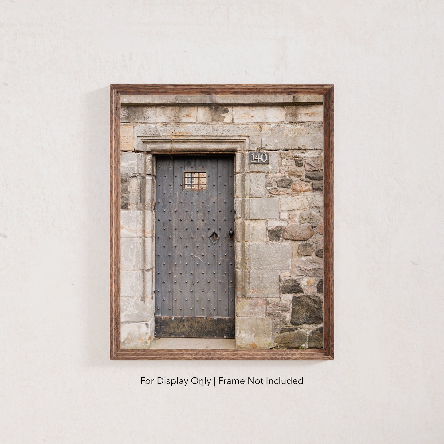 Rustic wooden door with iron studs set in a weathered stone wall, photographed in Edinburgh, Scotland.