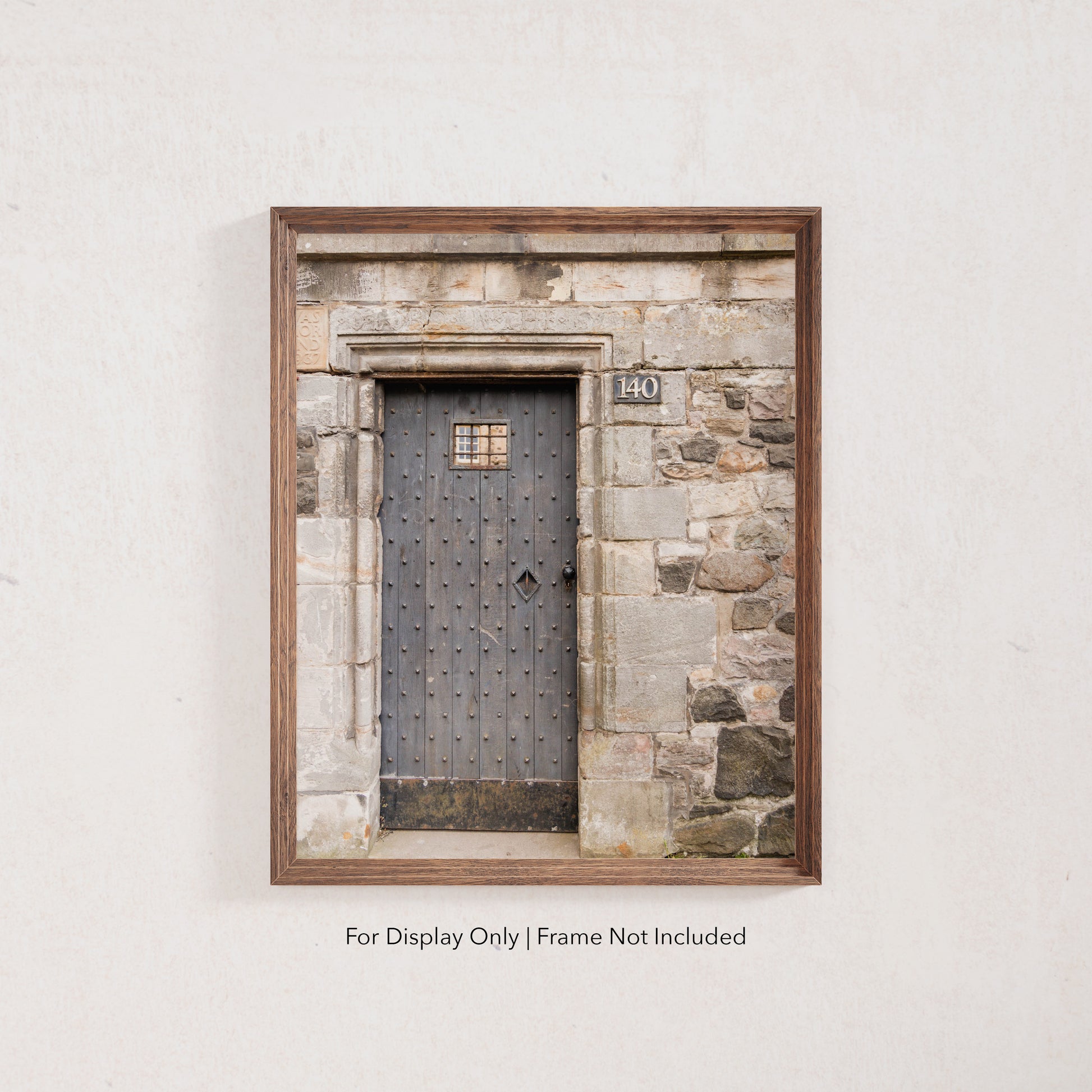 Rustic wooden door with iron studs set in a weathered stone wall, photographed in Edinburgh, Scotland.