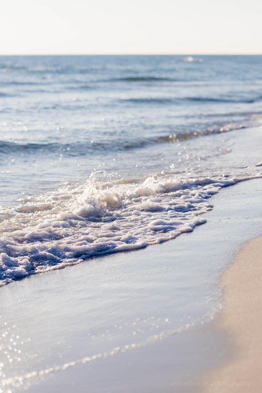 A photograph of a serene beach scene in Destin, Florida with gentle waves lapping at the shore.