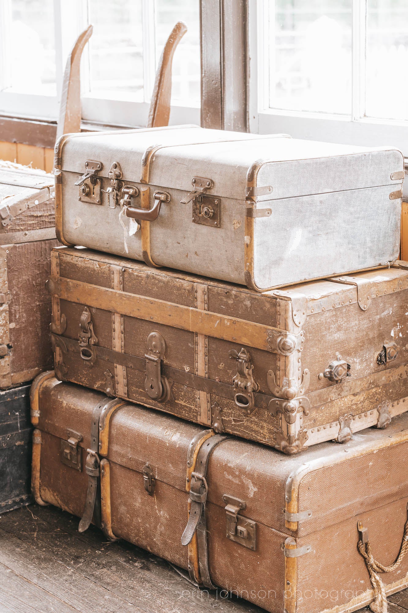 Stack of vintage suitcases and trunks with worn leather and metal details, photographed in soft natural light for a warm, rustic aesthetic.