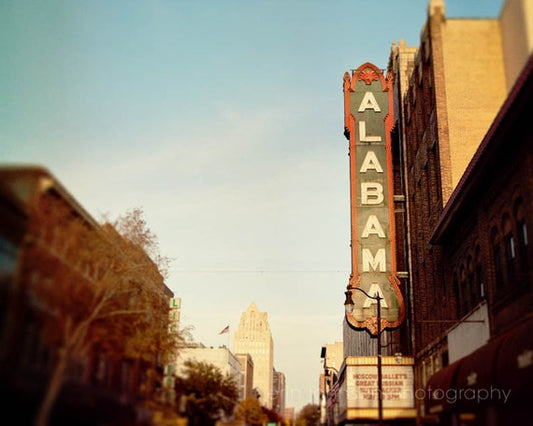 A photograph featuring the Alabama Theater in Birmingham, Alabama, with a vintage style movie sign on the side of a building.