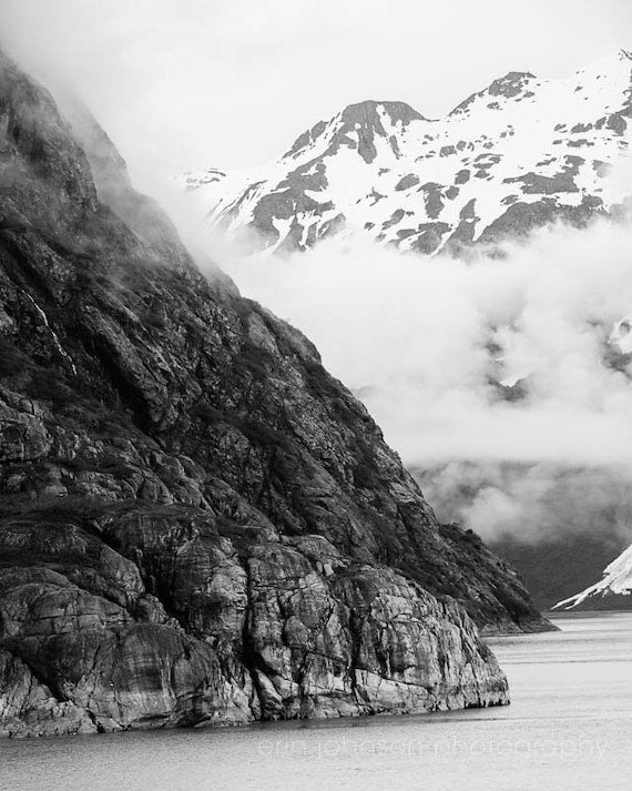 a black and white photo of a mountain and a body of water