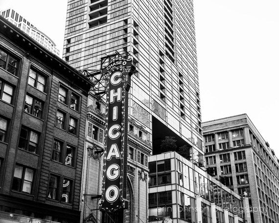 Black and white photograph of the Chicago Theater marquee and facade with a high-rise building in the background.
