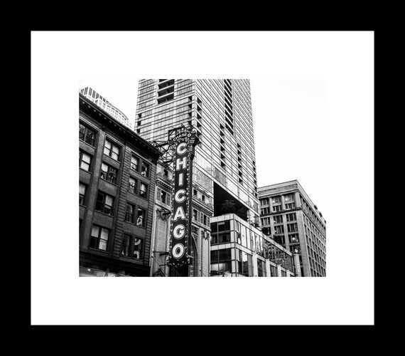 Black and white photograph of the Chicago Theater marquee and facade with a high-rise building in the background.