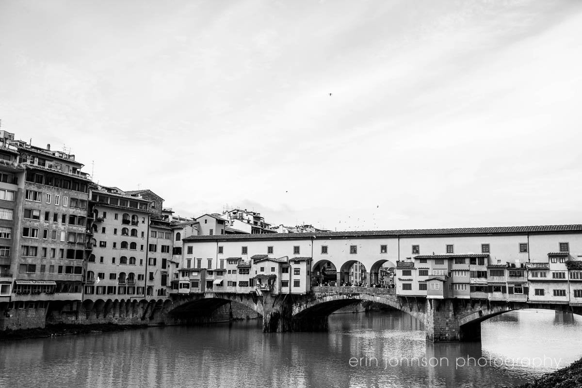 Black and white photo of Ponte Vecchio bridge and Arno River in Florence, Italy.