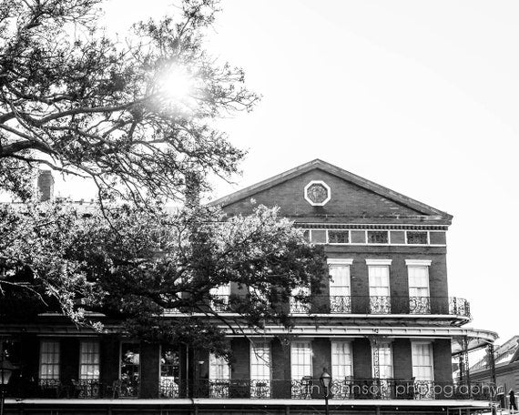 Black and white photograph of the Pontalba Building, featuring wrought-iron balconies and a red-brick facade, in New Orleans.
