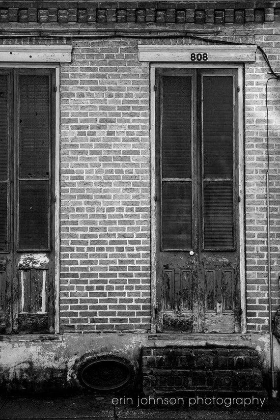 A black and white photograph of a weathered door in the French Quarter, New Orleans, with the address '808' visible.