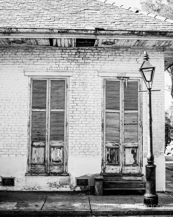 A black and white photograph of classic French Quarter architecture in New Orleans, featuring vintage shutters and doors.