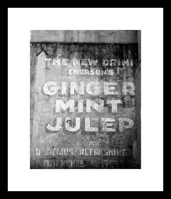 Black and white photograph of a vintage 'Ginger Mint Julep' advertisement in New Orleans' French Quarter.