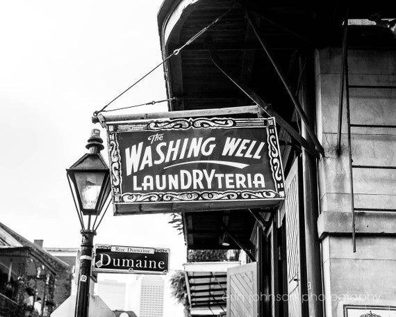 Black and white photograph of The Washing Well laundry sign in New Orleans' French Quarter.