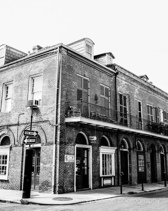 Black and white photograph of a French Quarter building with a balcony and ornate architectural details.