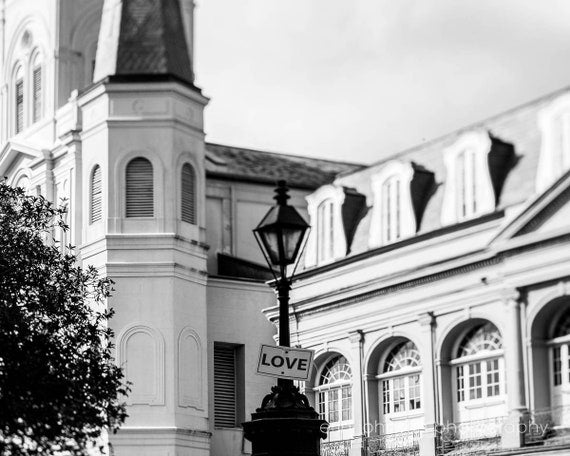 A black and white photograph of the St. Louis Cathedral in Jackson Square, New Orleans, with a 'LOVE' sign visible.