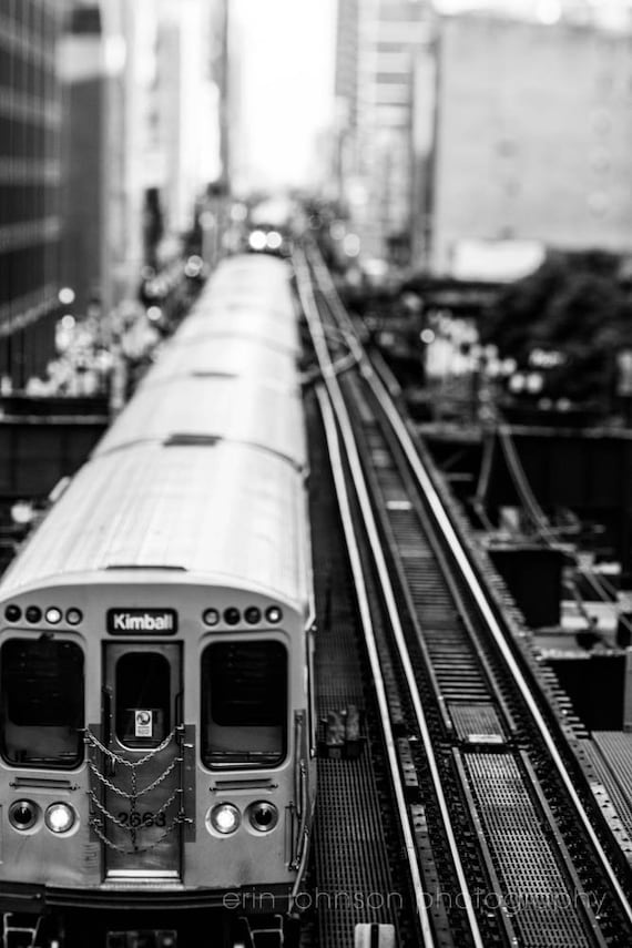 Black and white photograph of a CTA train on the Kimball line, with a focus on the train's movement and surrounding urban landscape.