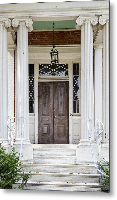 A metal print featuring a classical architectural design with a wooden door and frame, and a decorative lamp above the door.