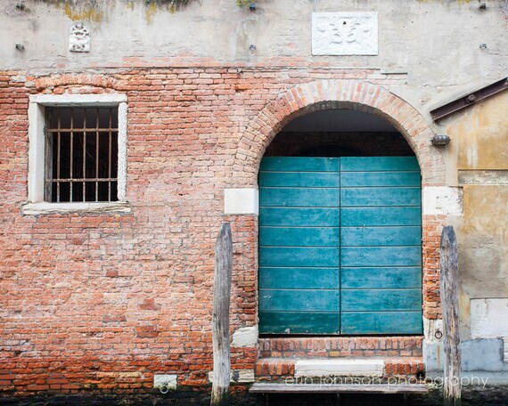 A photography print featuring a vibrant aqua blue doorway in Venice, Italy, with a brick wall in the background.