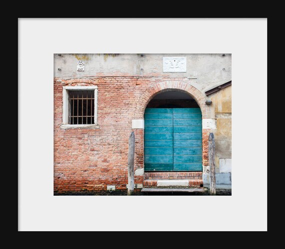 A photography print featuring a vibrant aqua blue doorway in Venice, Italy, with a brick wall in the background.