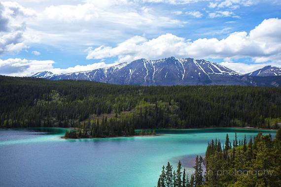 A landscape photograph featuring a serene lake with mountains in the background. Yukon Territory and Emerald Lake.