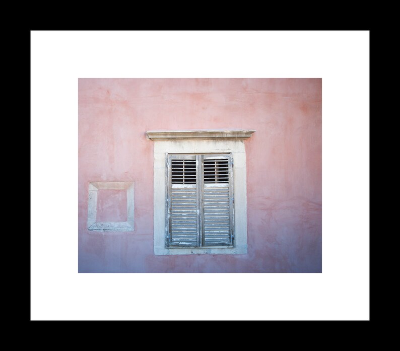 A photograph of a pink wall with a window and shutters in Dubrovnik, Crotia.