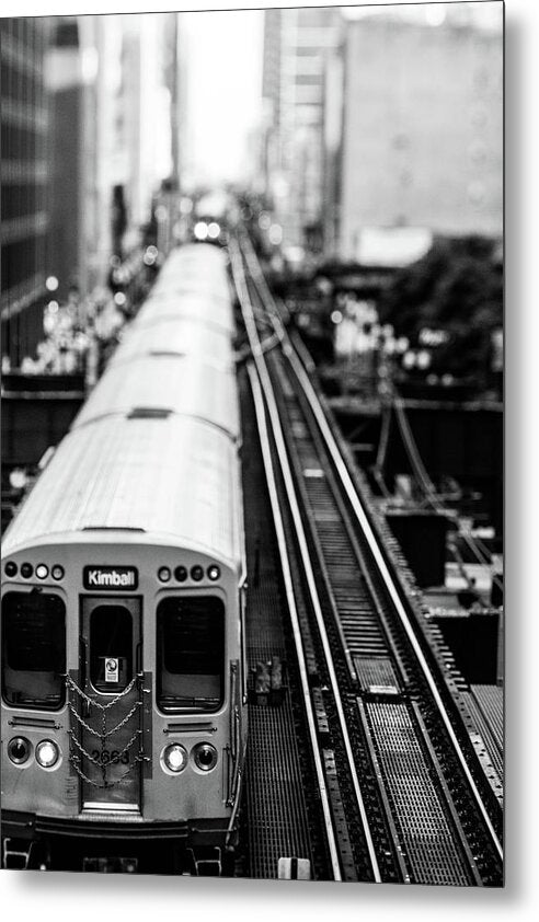 A black and white image of an elevated train on tracks, with a cityscape in the background.