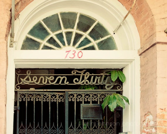 A photograph with orange tones featuring text that reads 'SEVEN THIRTY' in a decorative font, positioned on a building's entrance. New Orleans, Louisiana.