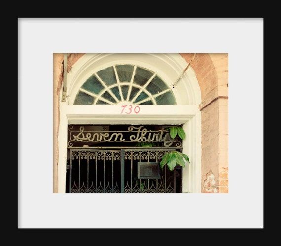 A photograph with orange tones featuring text that reads 'SEVEN THIRTY' in a decorative font, positioned on a building's entrance. New Orleans, Louisiana.