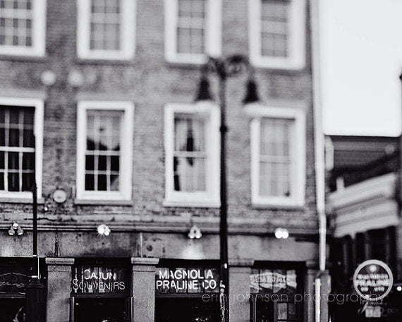 Black and white photograph of a building facade with a sign that reads 'Magnolia Praline Co' in New Orleans.