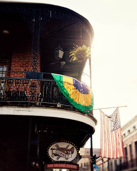 A photograph featuring a balcony with a Mardi Gras banner and an American flag, indicative of New Orleans architecture and spirit.