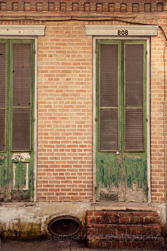 a brick building with two green doors and a fire hydrant