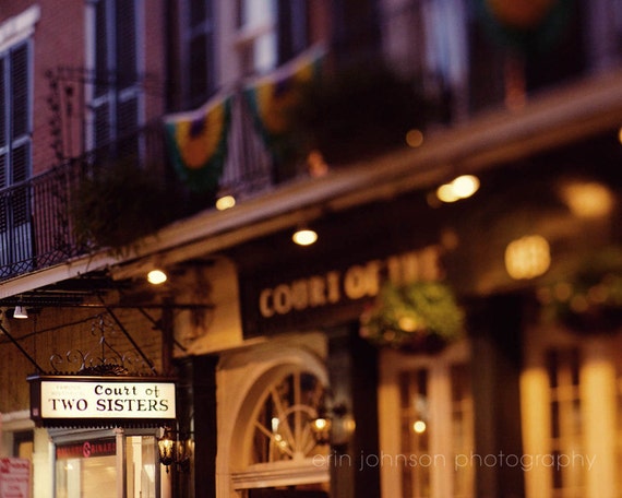 A photograph of the Court of Two Sisters restaurant in the French Quarter, showcasing the building's facade and decorative flags.