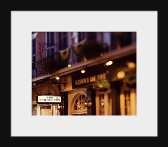 A photograph of the Court of Two Sisters restaurant in the French Quarter, showcasing the building's facade and decorative flags.