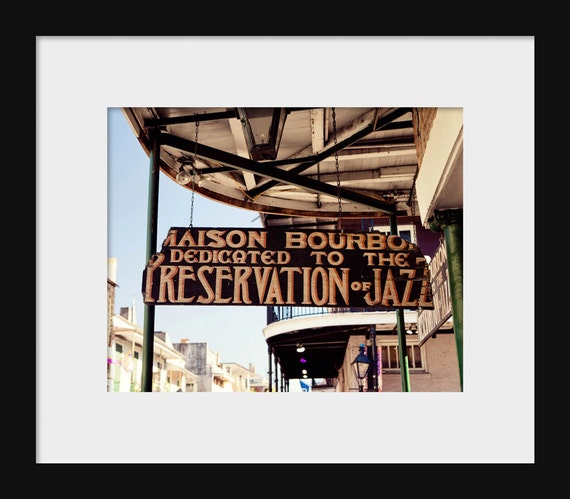 A sign with the text 'MAISON BOURBON dedicated to the preservation of jazz' on a balcony, in the French Quarter, New Orleans
