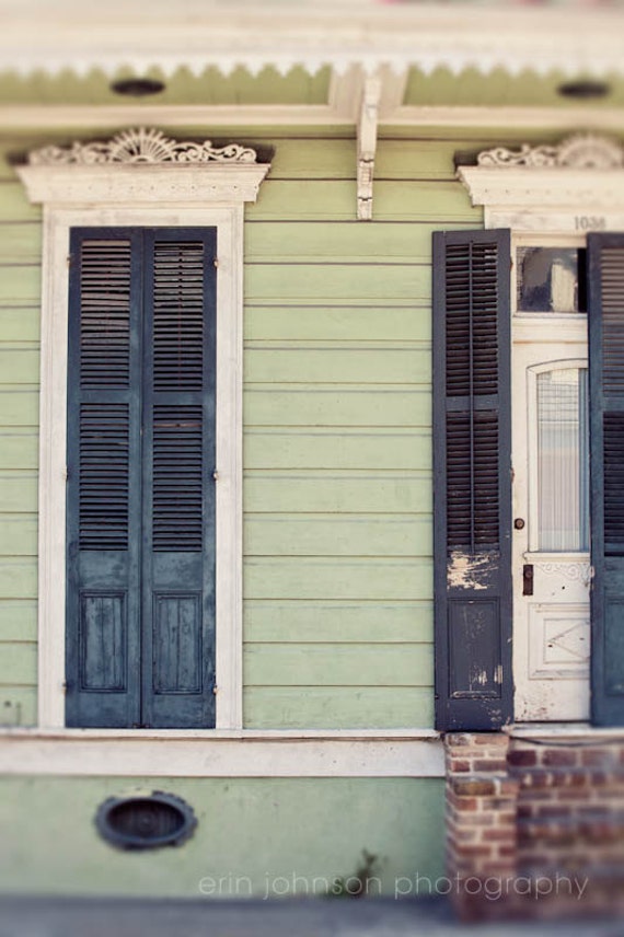 a green house with black shutters and a white door