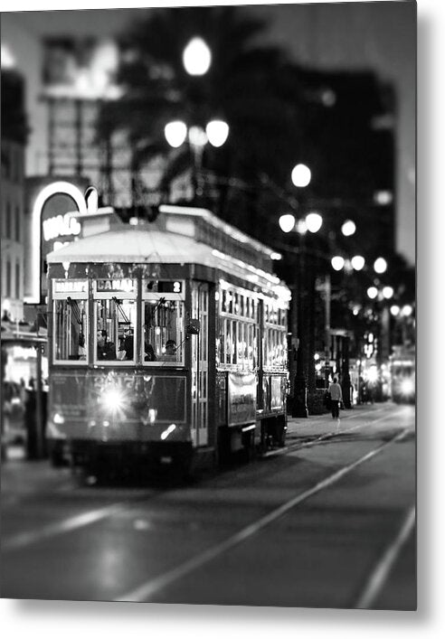 A vintage-style metal print featuring a New Orleans streetcar at night with illuminated streetlights and a bustling cityscape.