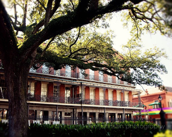 A photograph of the Pontalba Building in the French Quarter of New Orleans, with trees in the foreground and background.