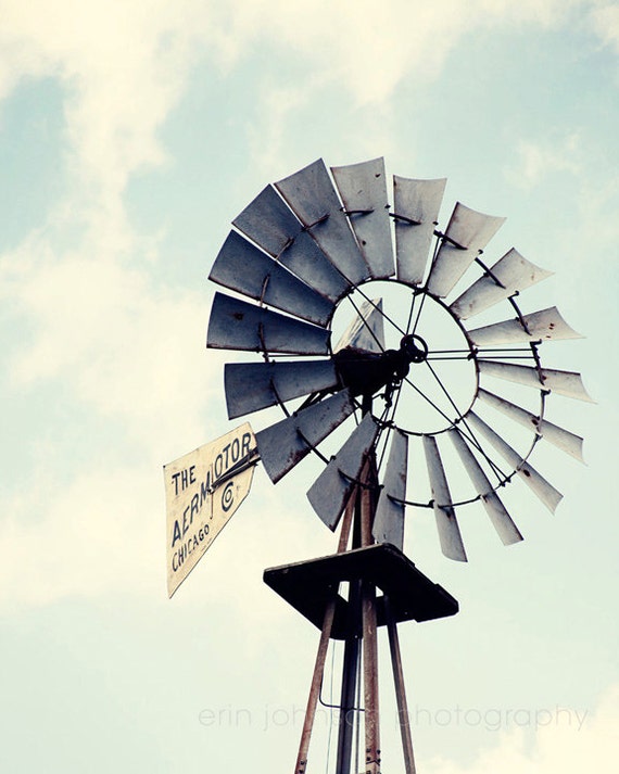 A color photograph of a windmill with a visible 'AEROMOTOR' sign with blue sky and clouds behind.