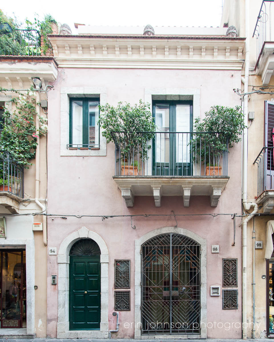 A photograph featuring a pink-colored building with a classical architectural design, possibly a part of a travel photography series.