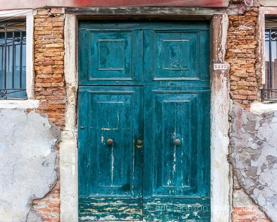 A teal door with a green frame set against a brown brick wall, representing a photography print with European charm. Venice Italy