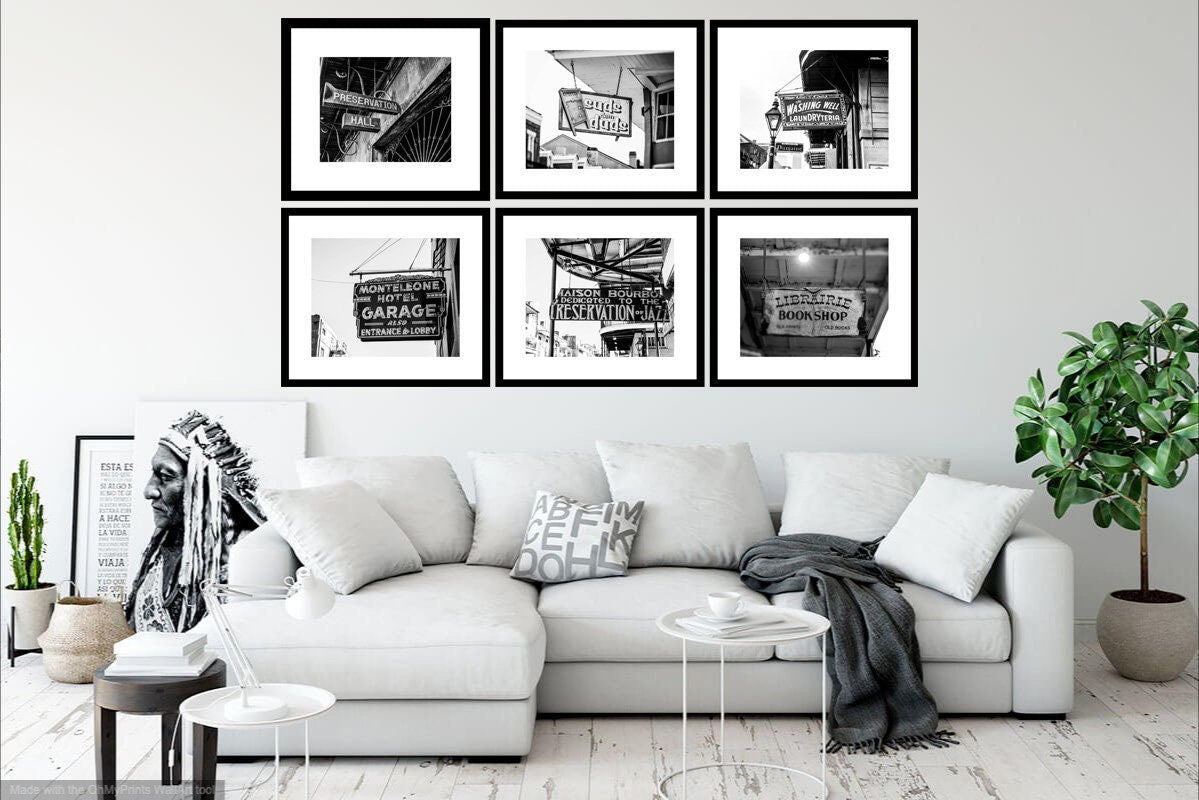 A set of six framed black and white New Orleans sign photography prints displayed on a wall above a white sofa, with a plant and decorative items in the room.