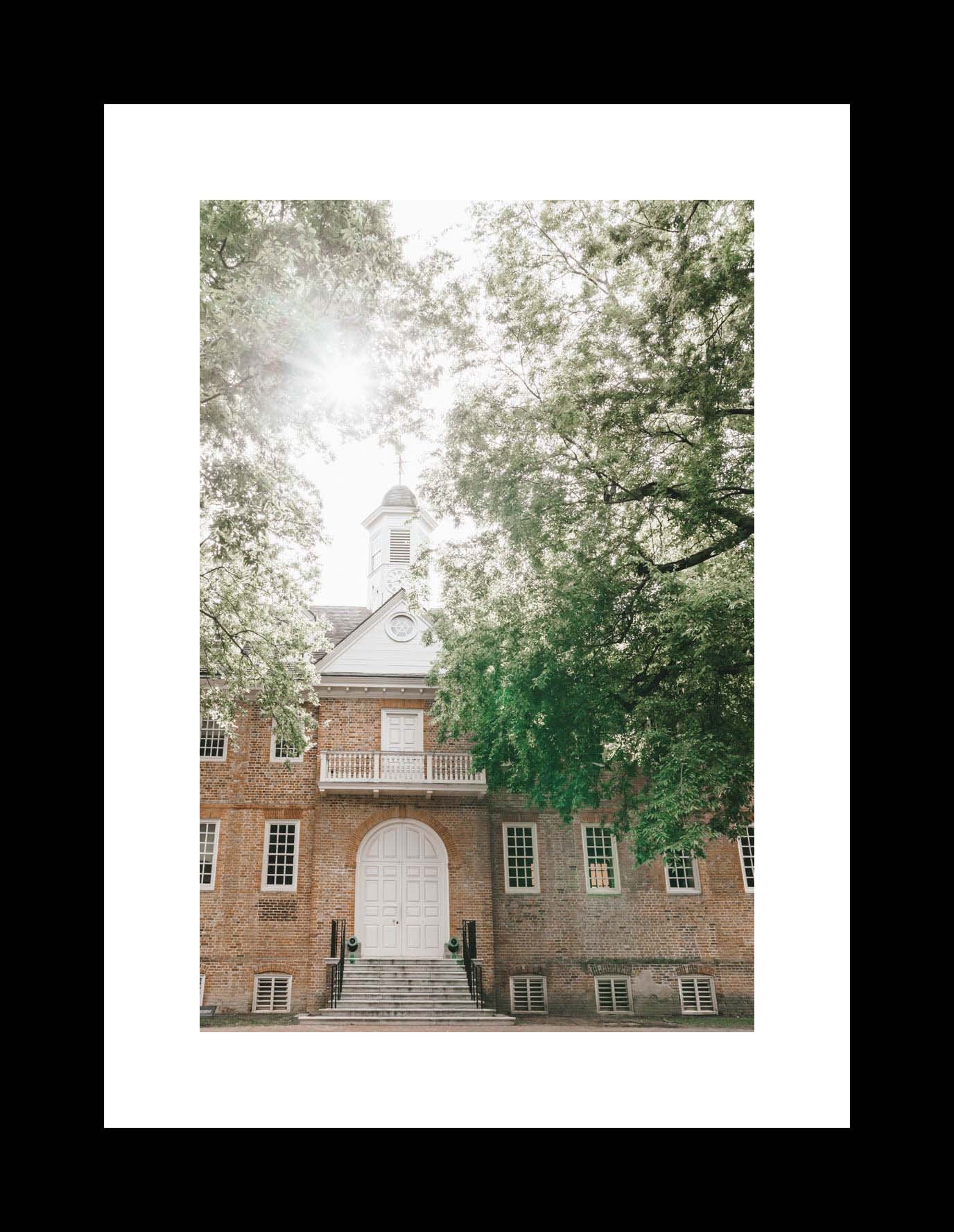Photography print of the Wren Building at the College of William & Mary, showing the front facade with a white door and steps, surrounded by green trees.