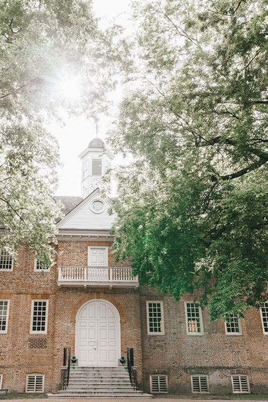 Photography print of the Wren Building at the College of William & Mary, showing the front facade with a white door and steps, surrounded by green trees.