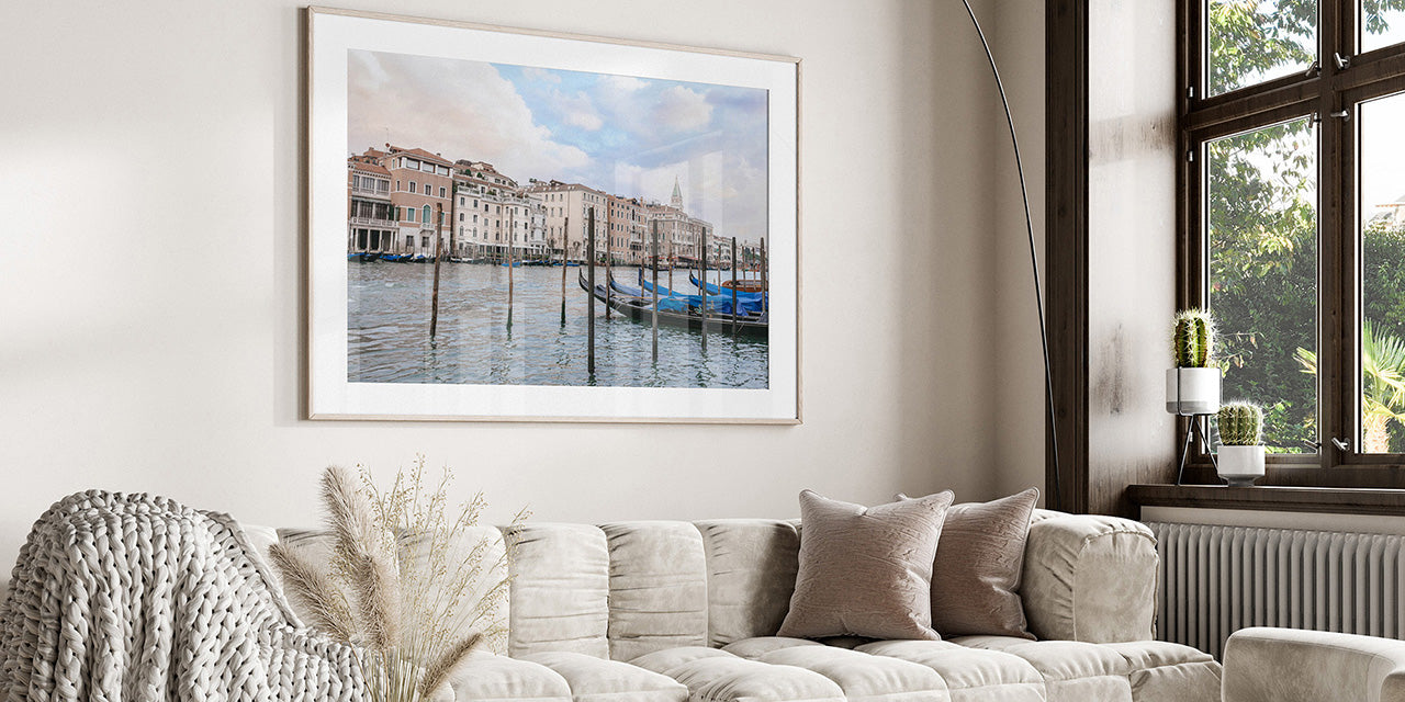 Living room with a framed picture of a canal on the wall above a sofa.