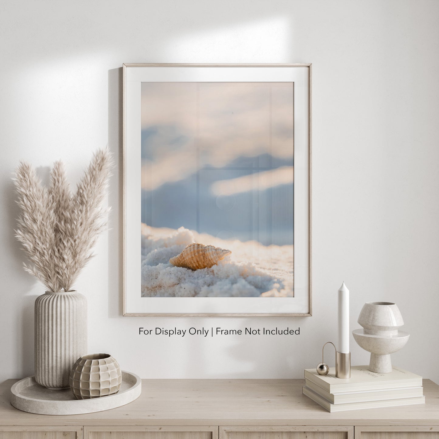 Seashell resting on white sand with a soft blurred background, coastal beach wall art.