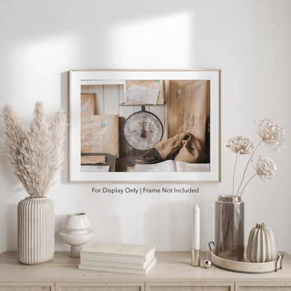 Rustic still life of vintage parcels wrapped in brown paper with stamps, stacked around a weathered post office scale.