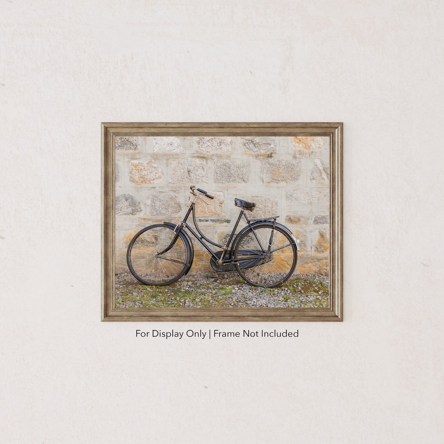 Vintage black bicycle leaning against a weathered stone wall, rustic countryside photography in neutral tones.