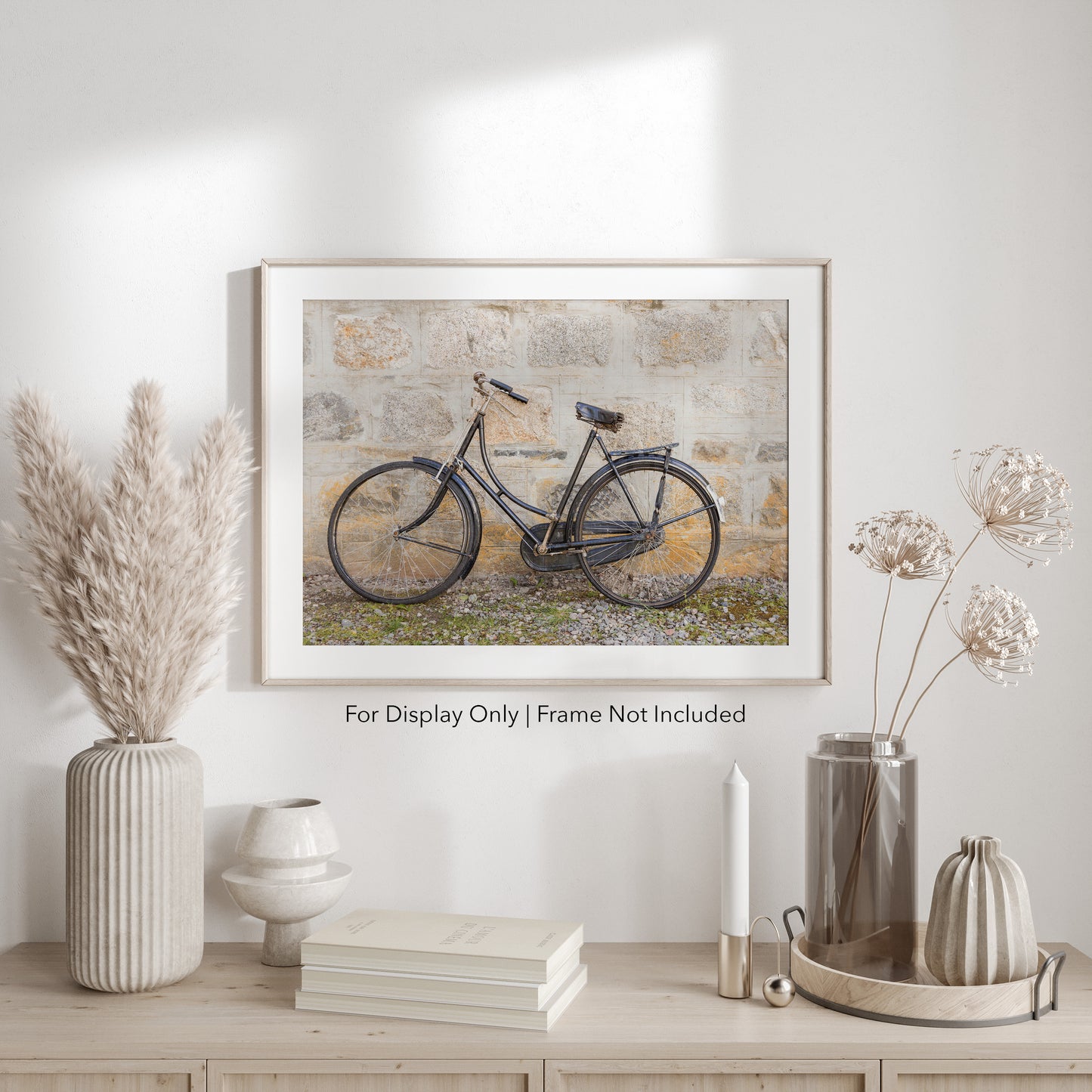 Vintage black bicycle leaning against a weathered stone wall, rustic countryside photography in neutral tones.