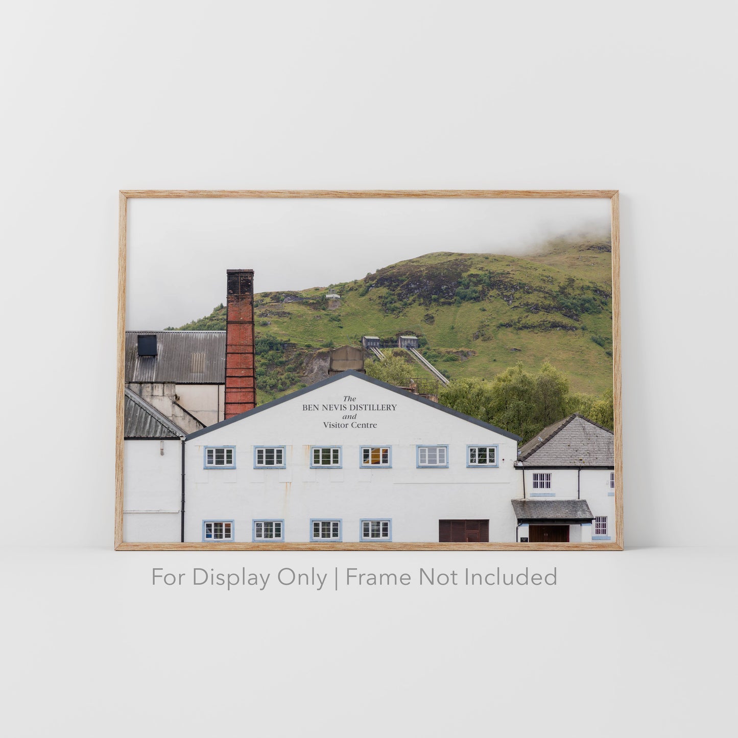 Ben Nevis Distillery and Visitor Centre in Fort William, Scotland, with whitewashed walls, red brick chimney, and Highland hills in the background.
