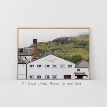 Ben Nevis Distillery and Visitor Centre in Fort William, Scotland, with whitewashed walls, red brick chimney, and Highland hills in the background.