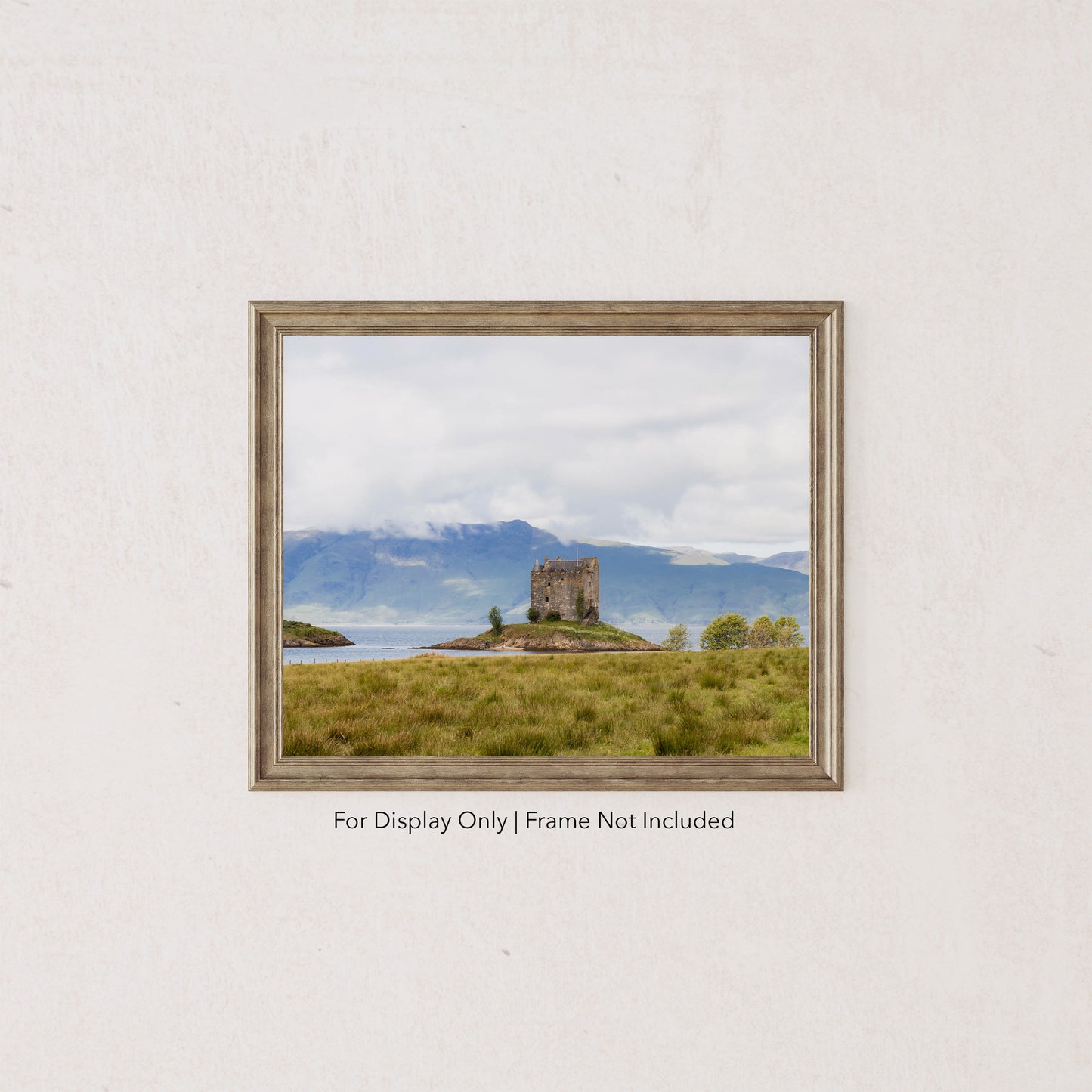 Castle Stalker on a small island in Loch Laich, Scottish Highlands, surrounded by mountains and water.