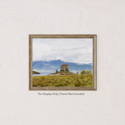 Castle Stalker on a small island in Loch Laich, Scottish Highlands, surrounded by mountains and water.